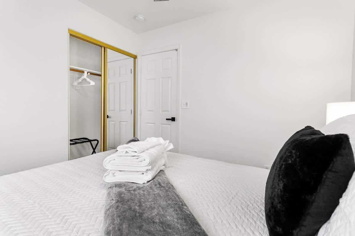 Een hotelkamer met een net opgemaakt bed, een kast met kledingroede en een deur met gouden omlijsting.