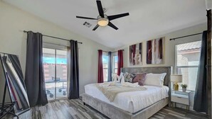 Ein Schlafzimmer mit einem großen Bett, einem Deckenventilator und Blick auf ein Gebäude.