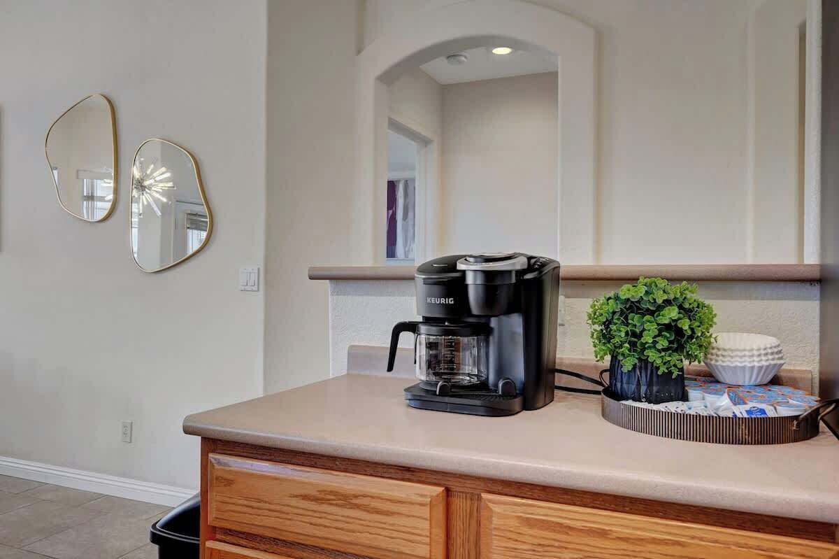 A kitchen with a coffee maker, a potted plant, and a bowl on the counter.