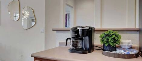 A kitchen with a coffee maker, a potted plant, and a bowl on the counter.