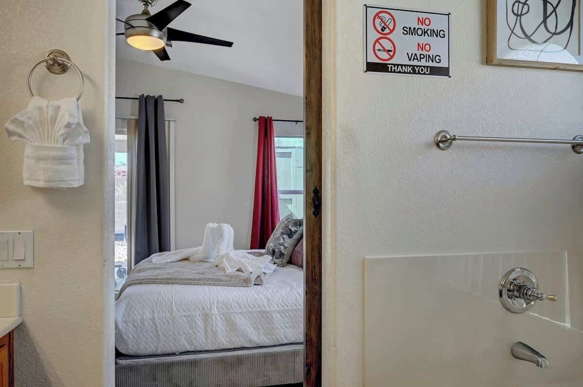 Hotelkamer met een bed, een plafondventilator, een handdoekrek en een bordje met de tekst 'niet roken/paffen'.
