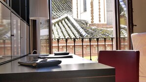 Ein modernes Zimmer mit einem großen Fenster, einem Schreibtisch, einem roten Sessel und einer Lampe.