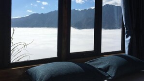 A room with a large window offering a view of mountains and clouds. - Sapa Mackeno (Sa Pa)