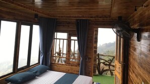 A wooden cabin room with a bed, large windows, and a view of the outdoors. - Sapa Mackeno (Sa Pa)