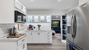 A modern kitchen with white cabinetry, a stainless steel refrigerator, and a wooden countertop. - Walk to Old Town | Pool • Hot Tub • EV Charger (Scottsdale)