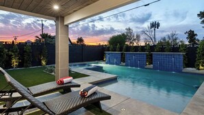 A backyard with a swimming pool, two lounge chairs, and a covered patio area. - Walk to Old Town | Pool • Hot Tub • EV Charger (Scottsdale)