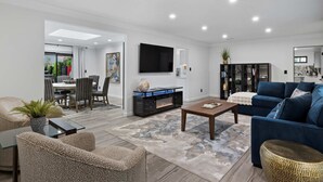 A modern living room with a fireplace, a sofa, a coffee table, and a TV mounted on the wall. - Walk to Old Town | Pool • Hot Tub • EV Charger (Scottsdale)