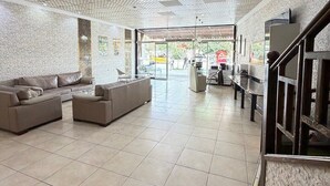Un vestíbulo amplio con techo alto, suelo de baldosas y una zona de estar con sofás y sillones.