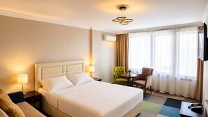 Una habitación de hotel con una cama grande, un escritorio, una silla y un televisor.
