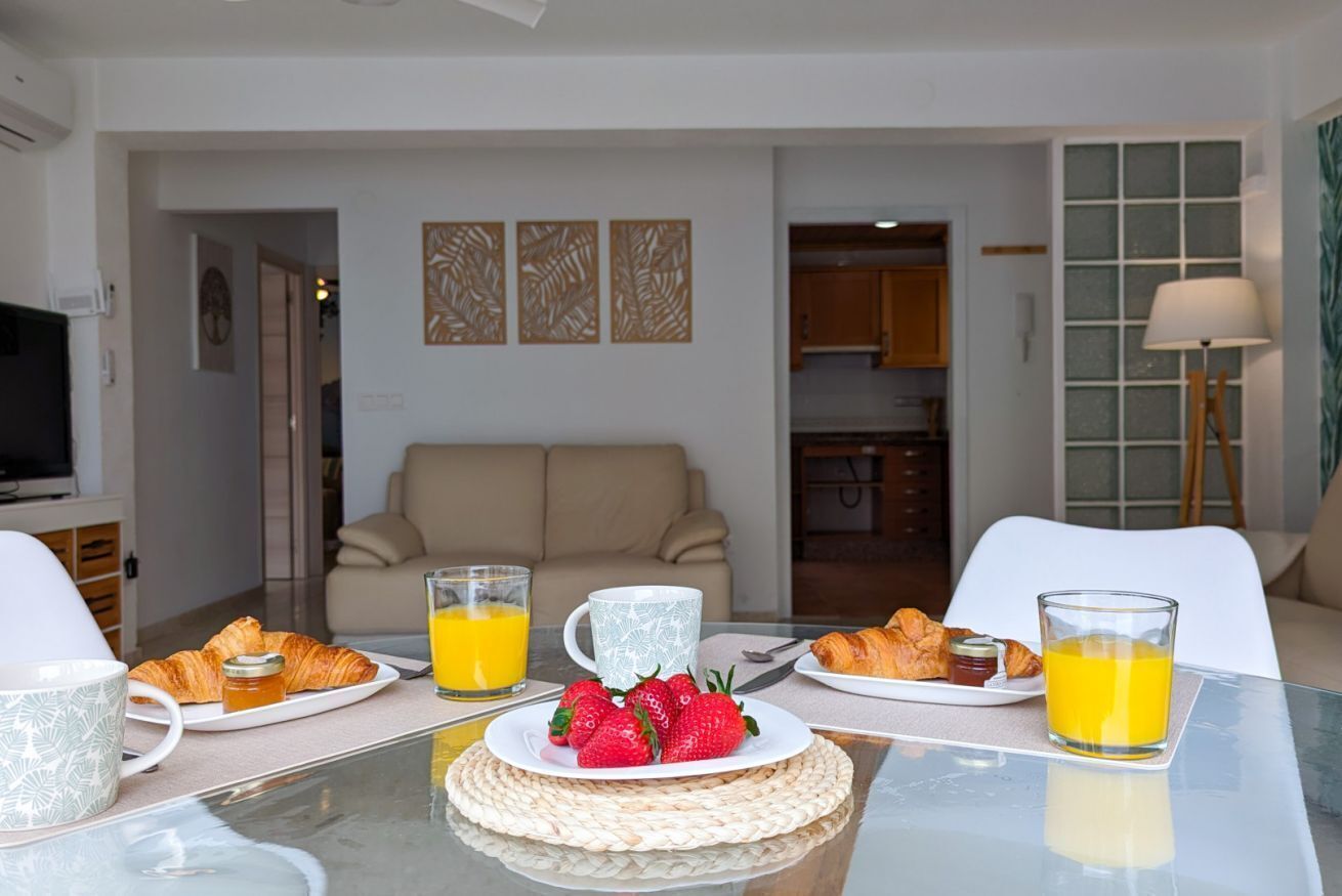 A breakfast setting with croissants, strawberries, and orange juice on a table.
