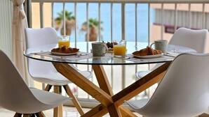 A glass-top table with breakfast items, white chairs, and a view of the sea. - GRAN SOL sea front apartment (Calpe)