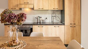 A modern kitchen with wooden cabinets, a stainless steel sink, and a dining table with white chairs. - Miki Mhouse by Interhome (Lago di Mezzola)