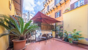 A courtyard with a red umbrella, potted plants, and a tiled floor. - Room-camera Doppia in History House (Rome)