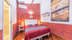 A bedroom with a red wall, a bed with a red and gray blanket, two bedside tables with lamps, and a large framed picture on the wall. - Room-skylight Double Room in History Hou (Rome)