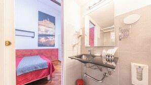 A bathroom with a sink, mirror, and towel rack. There is a bed with a red blanket in the adjacent room. - Room-skylight Double Room in History Hou (Rome)