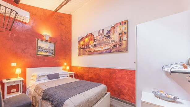 Una camera d'albergo con un letto, comodini, una lampada, un quadro e una mensola a muro.