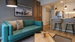 A modern living room with a teal sofa, a coffee table, and a kitchen area with bar stools. - w * | Marvelous 1BR in the Heart of Barranco (Lima)