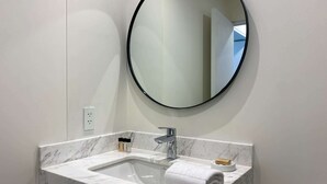 A bathroom with a marble sink, a round mirror, and a towel on the counter. - w * | Marvelous 1BR in the Heart of Barranco (Lima)