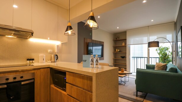 A modern kitchen with wooden cabinets, a built-in oven, and pendant lighting. - w * | Marvelous 1BR in the Heart of Barranco (Lima)