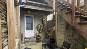 A patio area with a barbecue grill, two tables, and chairs. A wooden staircase leads to a door. - Duplex 31m2 Centre Manche Proche Plage du Débarquement, Mont st Michel, Chausey (Marigny-le-Lozon)