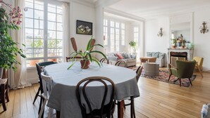 Un salon spacieux avec une table ronde, des sièges confortables, une cheminée et de grandes fenêtres.
