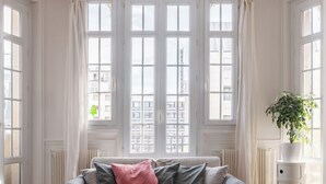Une pièce avec une grande fenêtre, un radiateur, une commode blanche et une plante.