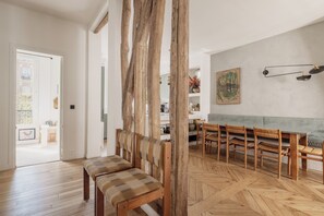 Un comedor con bancos y sillas de madera, un suelo con dise ño de espiga y un cuadro en la pared.