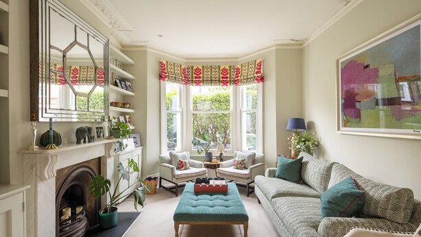 Un salon chaleureux avec une cheminée, deux fauteuils, un canapé et un grand tableau.