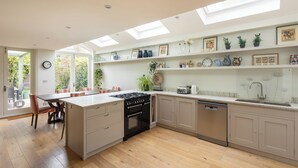 Une cuisine moderne dotée d’un îlot central, d’appareils électroménagers intégrés et d’une lucarne.