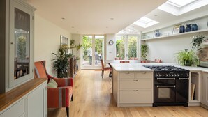 Une cuisine moderne dotée d’un îlot central, d’un four encastré et d’un coin repas avec des chaises et une table.