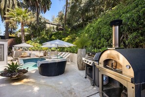 An outdoor patio with a pool, lounge chairs, a barbecue grill, and a hot tub.