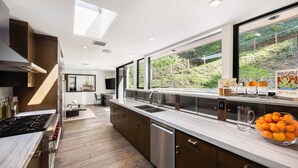 A modern kitchen with a large window, a built-in stove, and a countertop with a bowl of oranges. - Villa Aman by Stay Awhile Villas (Beverly Hills)