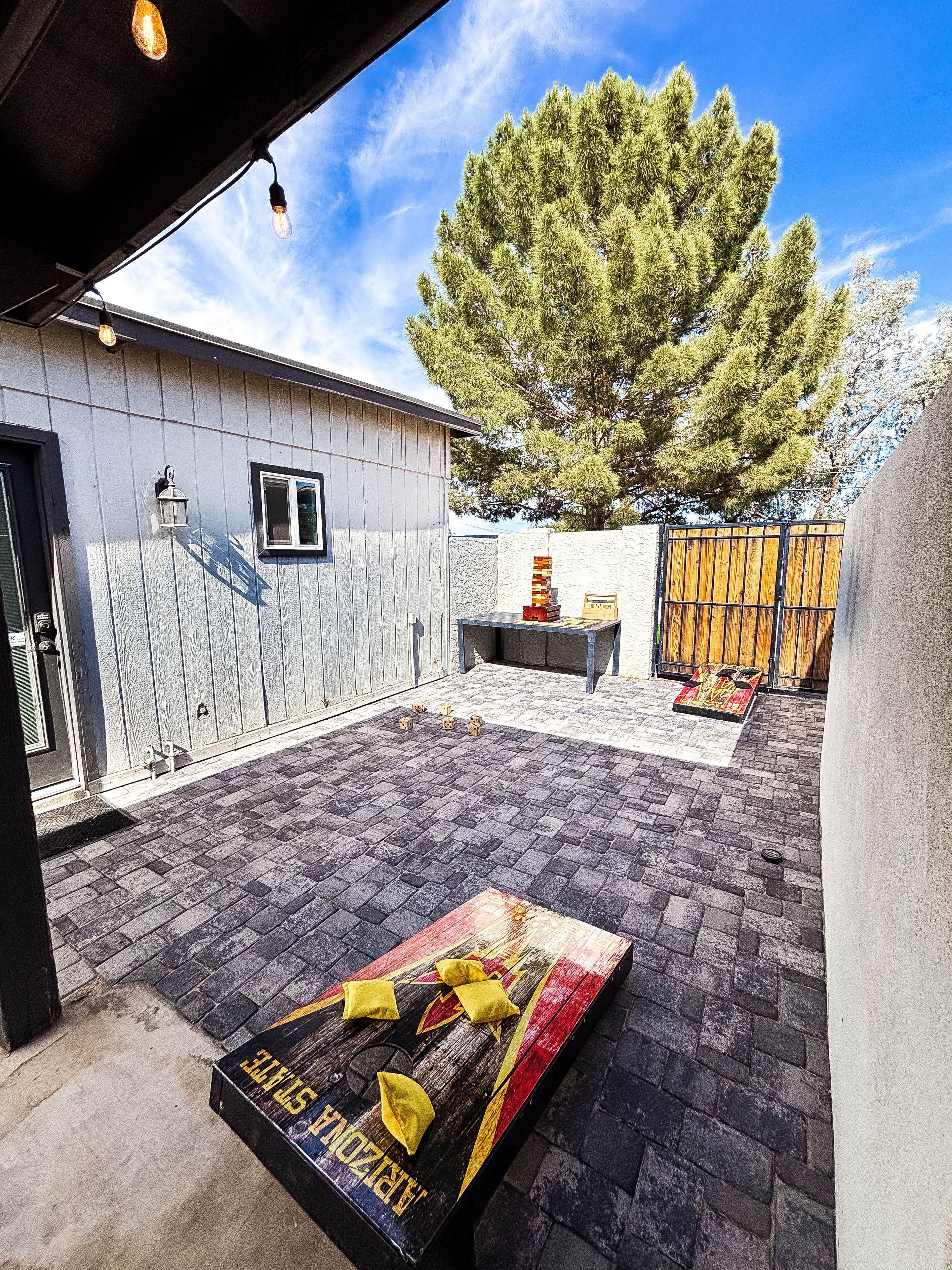 A patio area with a brick floor, a wooden table, and a colorful board game.