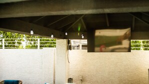 Un espace extérieur avec un jacuzzi, une terrasse en bois, des fauteuils en osier et un mur blanc en arrière-plan.