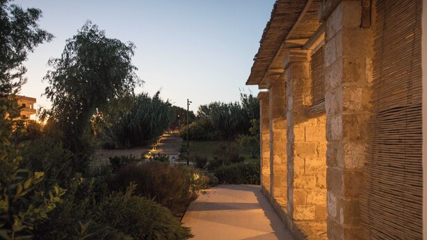 A pathway leading to a stone building with a traditional design, surrounded by greenery and trees. - 4 bedroom condo in apulia (Puglia)