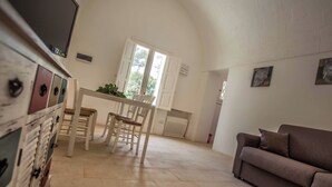 A spacious room with a dining table and chairs, a sofa, and a cabinet with drawers. - 4 bedroom condo in apulia (Puglia)