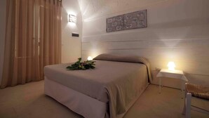 A bedroom with a bed, a bedside table with a lamp, a chair, and a wall-mounted artwork. - 4 bedroom condo in apulia (Puglia)