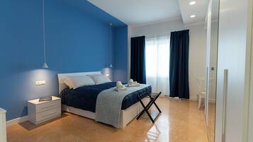 A modern bedroom with a bed, bedside tables, a hanging light fixture, and a window with curtains.