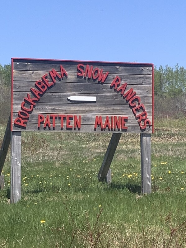 Un letrero de madera con el texto "Rocky Mountain Snow Rangers" y "Pattens Maine" que indica una ubicación.