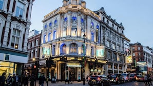 Un bâtiment historique abritant un théâtre, avec une façade classique, de nombreux balcons et un auvent publicitaire annonçant un film.