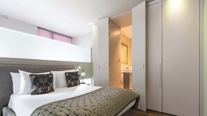 A bedroom with a bed, bedside table, lamp, and a wardrobe. - Duplex Apartment · Covent Garden · Sleeps 4 (Greater London)