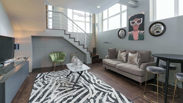 A modern living room with a staircase, a sofa, a coffee table, and a bar area. - Duplex Apartment · Covent Garden · Sleeps 4 (Greater London)