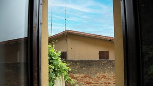A view through a doorway to a building with a brick wall and a red roof. - La Casa di Andrea (Gardone Riviera)