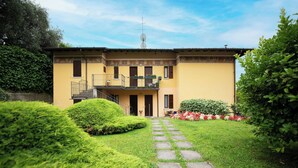 A two-story building with a balcony, a staircase, and a well-maintained garden with a stone pathway. - La Casa di Andrea (Gardone Riviera)
