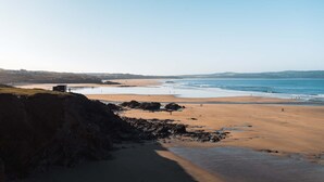 A coastal beach scene with a rocky outcrop, a small building, and a clear view of the sea. - Clearwater House - sleeps 6 guests  in 3 bedrooms (Hayle)