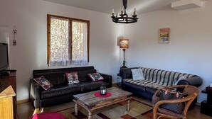 Ett vardagsrum med en soffa, två fåtöljer, ett soffbord, en tv och en lampa.