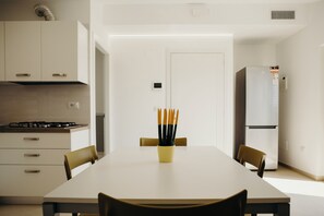 A modern kitchen with white cabinets, a stove, and a dining table with chairs.