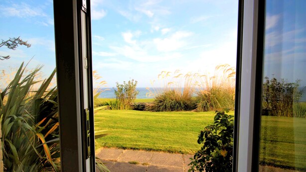 A view through a window of a grassy area with a pathway leading to a body of water.