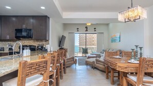 A modern kitchen with granite countertops, wooden chairs, and a dining table.