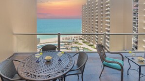 Ein Balkon mit Blick auf den Ozean und ein Resort, ausgestattet mit einem runden Tisch, Stühlen und einem kleinen Pool.